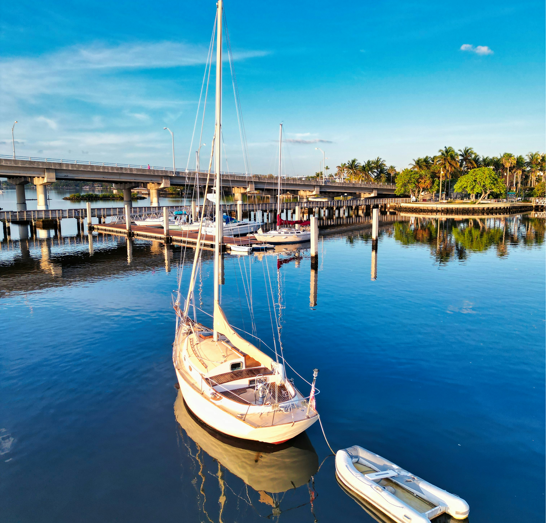 A sailboat is docked in the water near a bridge