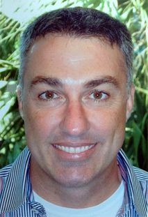A man in a striped shirt is smiling for the camera.