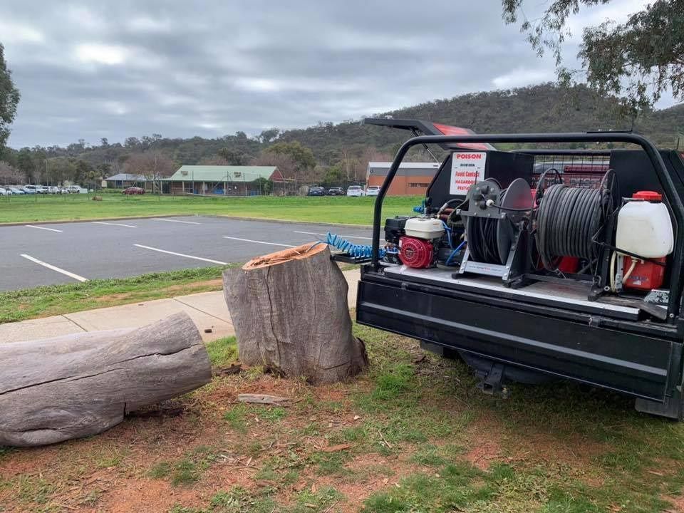 A Truck With A Stump In The Back Is Parked In A Grassy Field — Cantips Pest Control in Albury, NSW