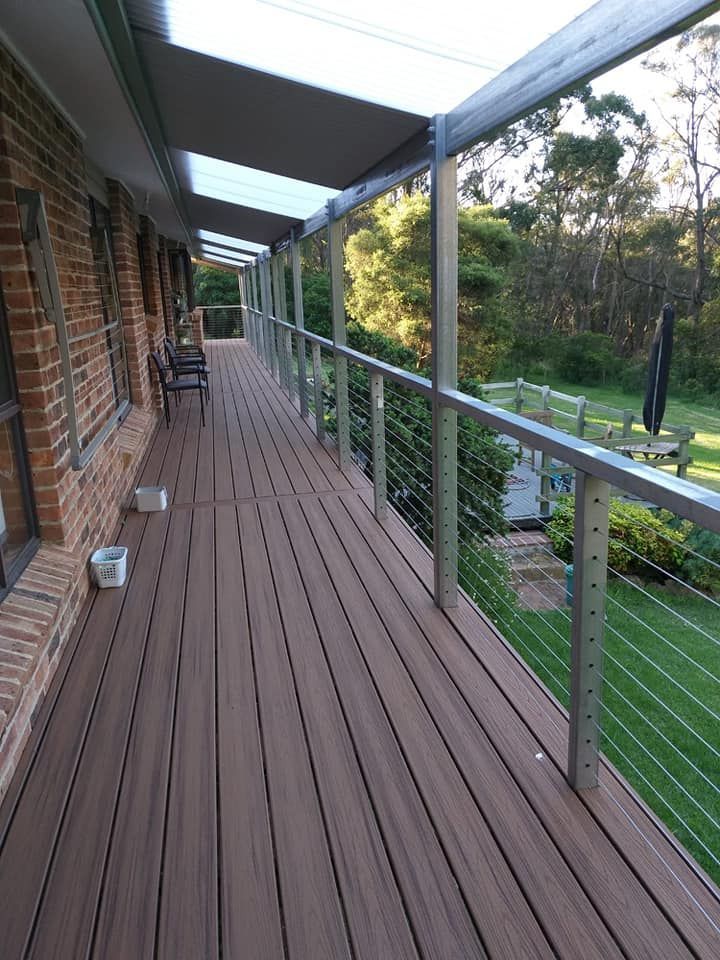 A Long Wooden Deck With a Metal Railing and a Brick Building in the Background — Proweld Steel Fabrication In Nowra, NSW