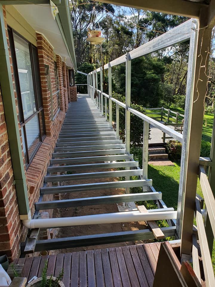 A Wooden Deck is Being Built on the Side of a Brick House — Proweld Steel Fabrication In Nowra, NSW