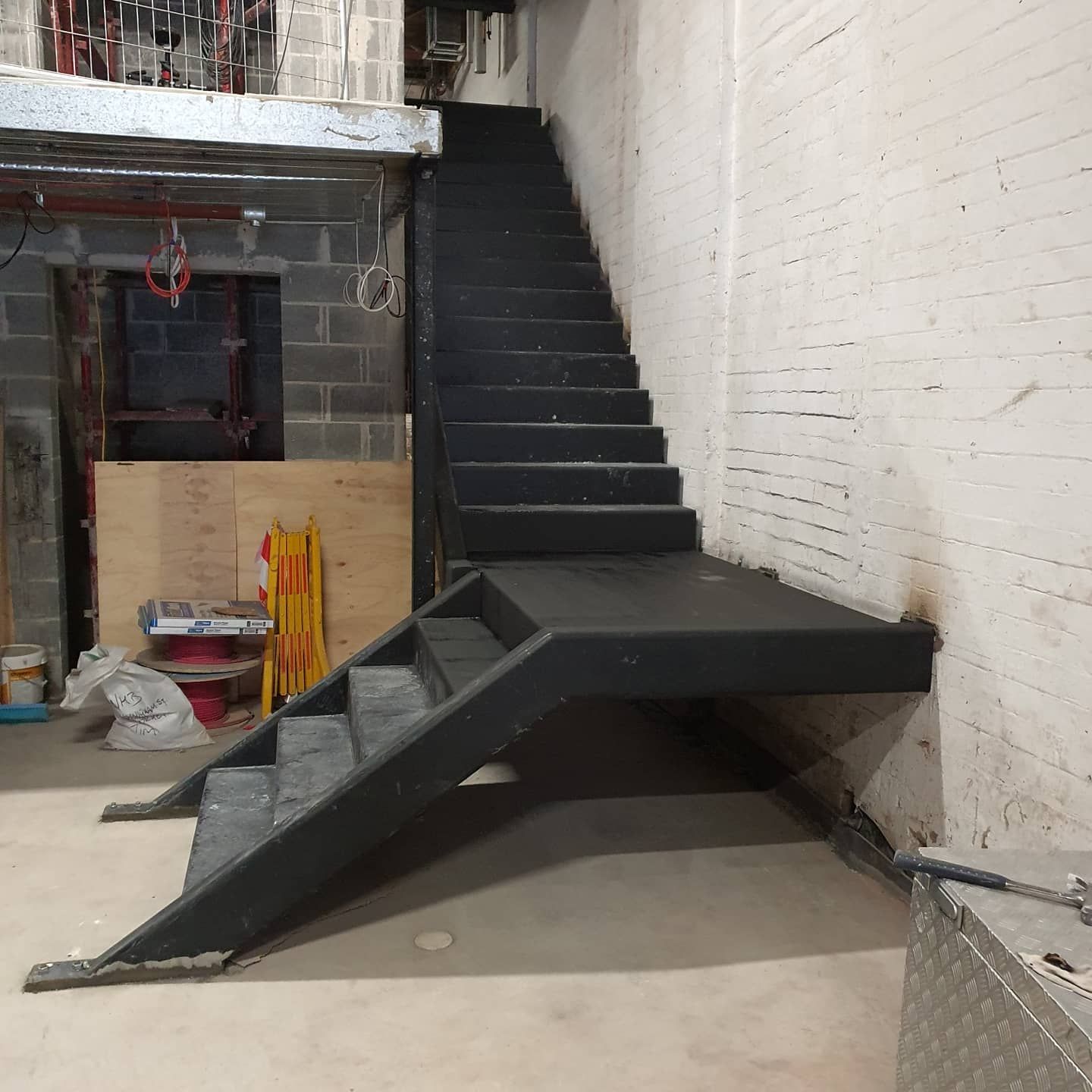 A Black Staircase in a Room With a Brick Wall — Proweld Steel Fabrication In Shellharbour, NSW