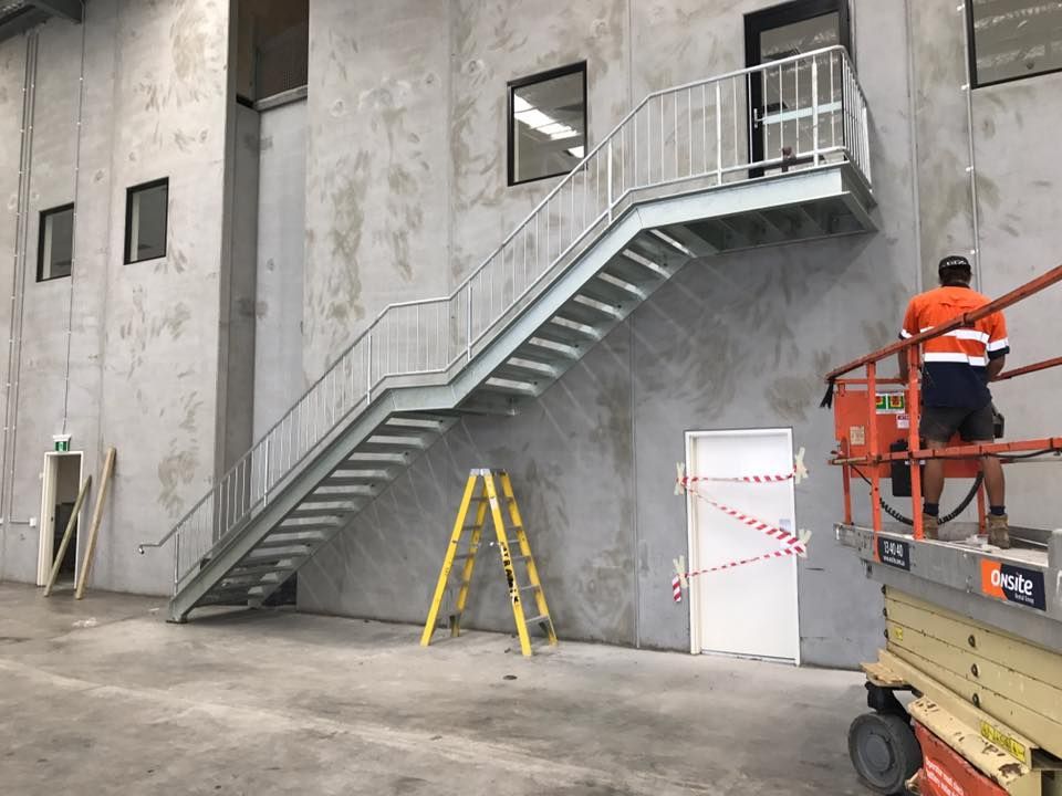 A Man is Sitting on a Lift Next to a Set of Stairs — Proweld Steel Fabrication In Sydney, NSW