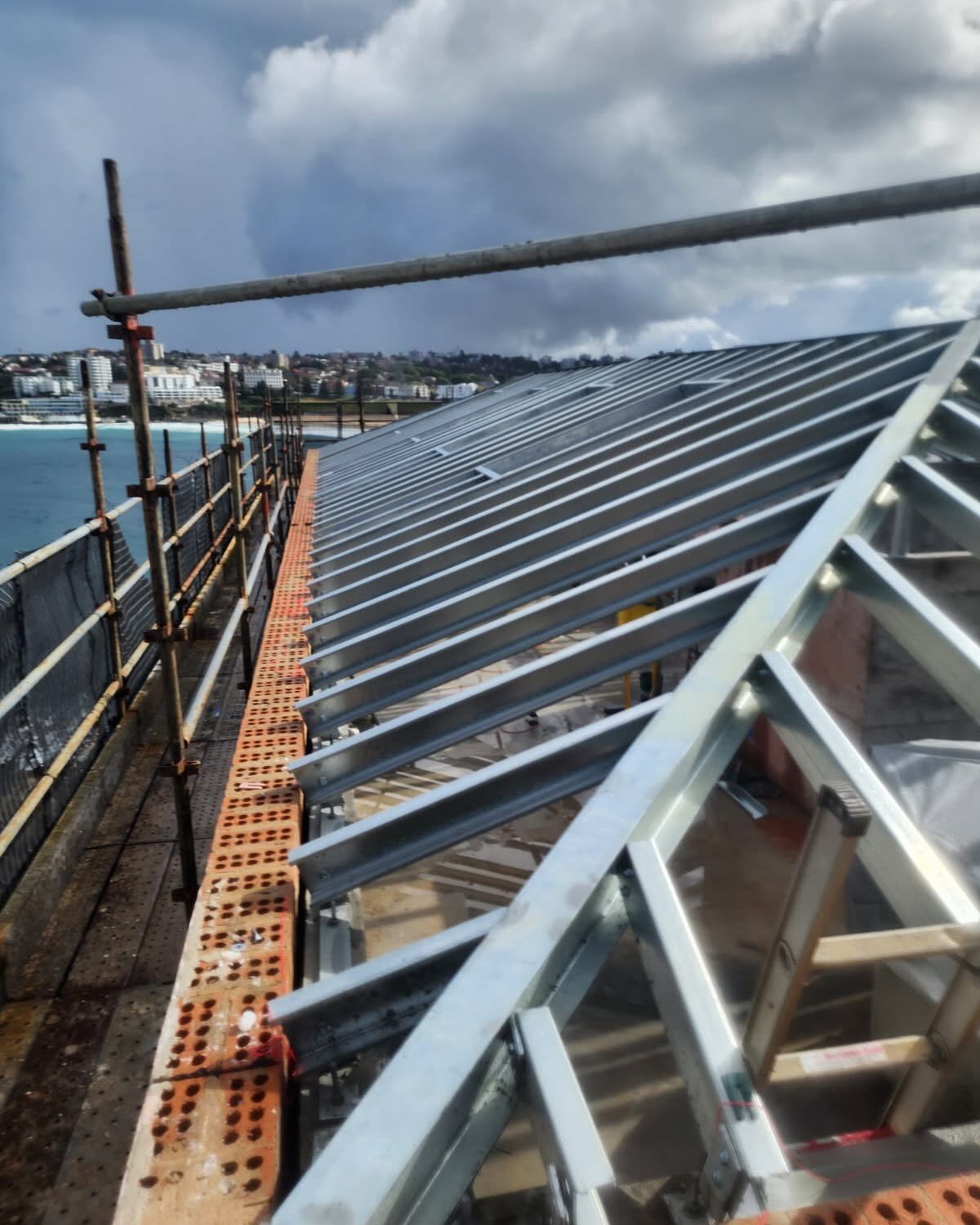 A Roof That is Being Built With Scaffolding Around It — Proweld Steel Fabrication In Unanderra, NSW