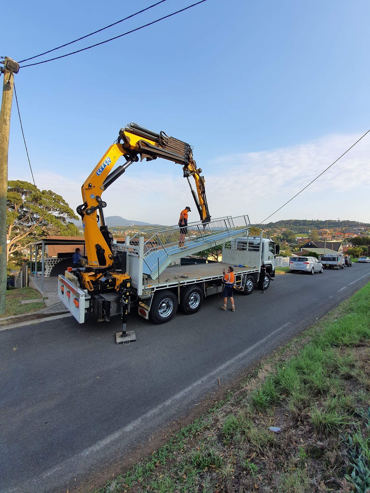 A Truck with A Crane Lifts Metal Beams — Proweld Steel Fabrication In Shellharbour, NSW