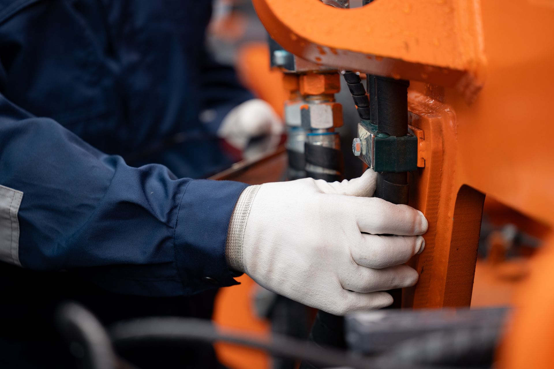 A man wearing white gloves is working on a machine.