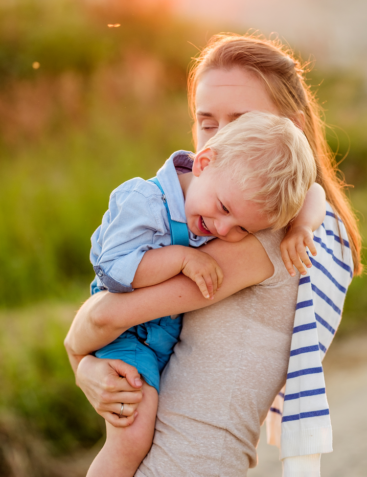Woman holding a laughing child, golden sunlight.