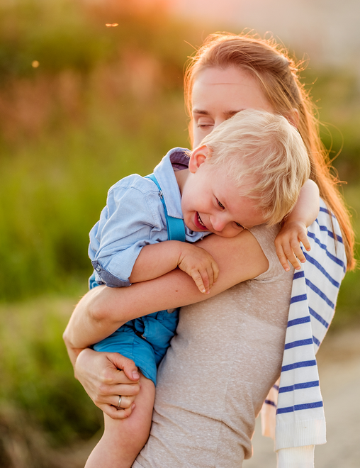 Woman holding a laughing child, golden sunlight.