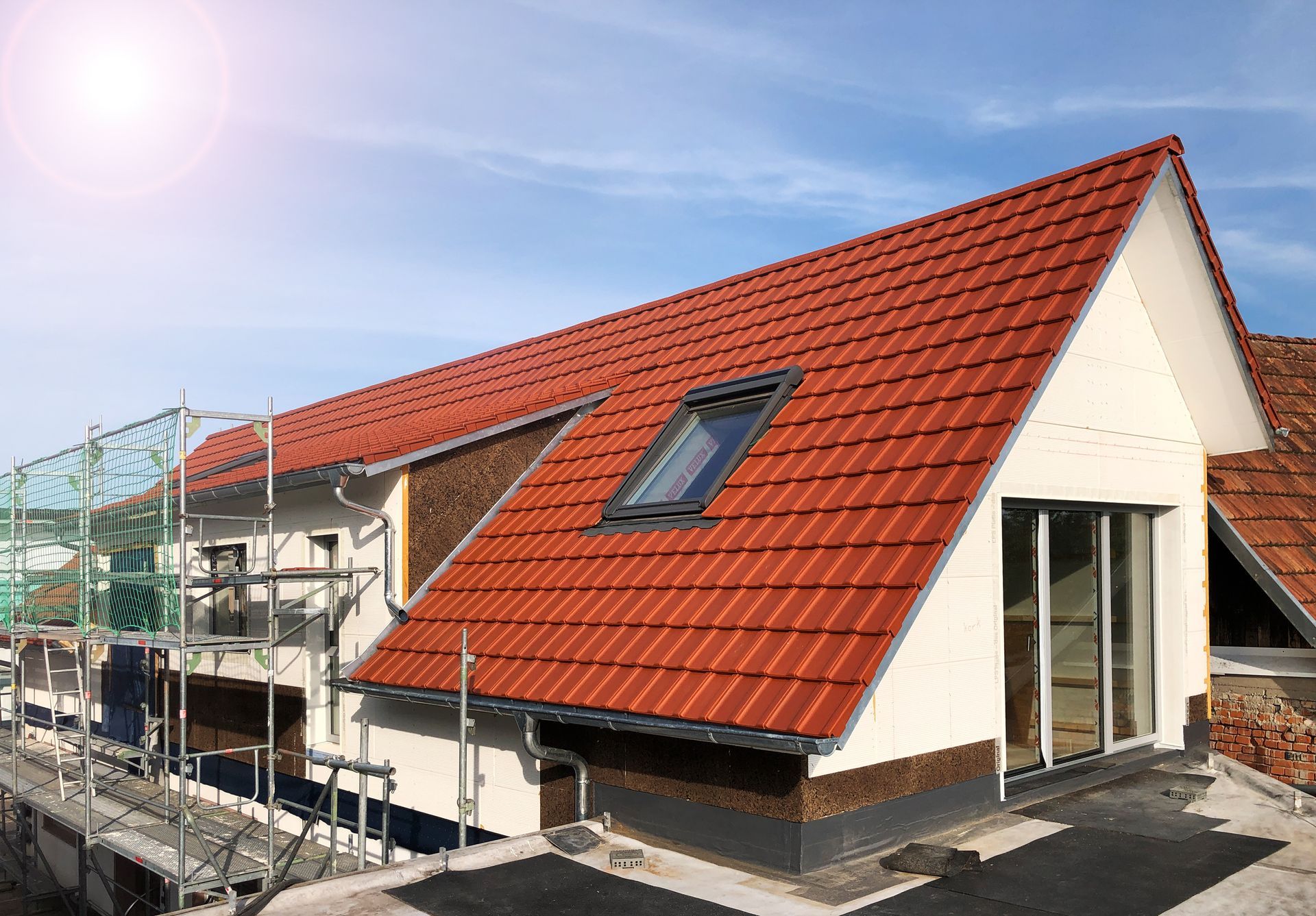 Eine Dachgaube mit Glastür. Ebenfalls zu sehen ein Dachfenster und ein Gerüst