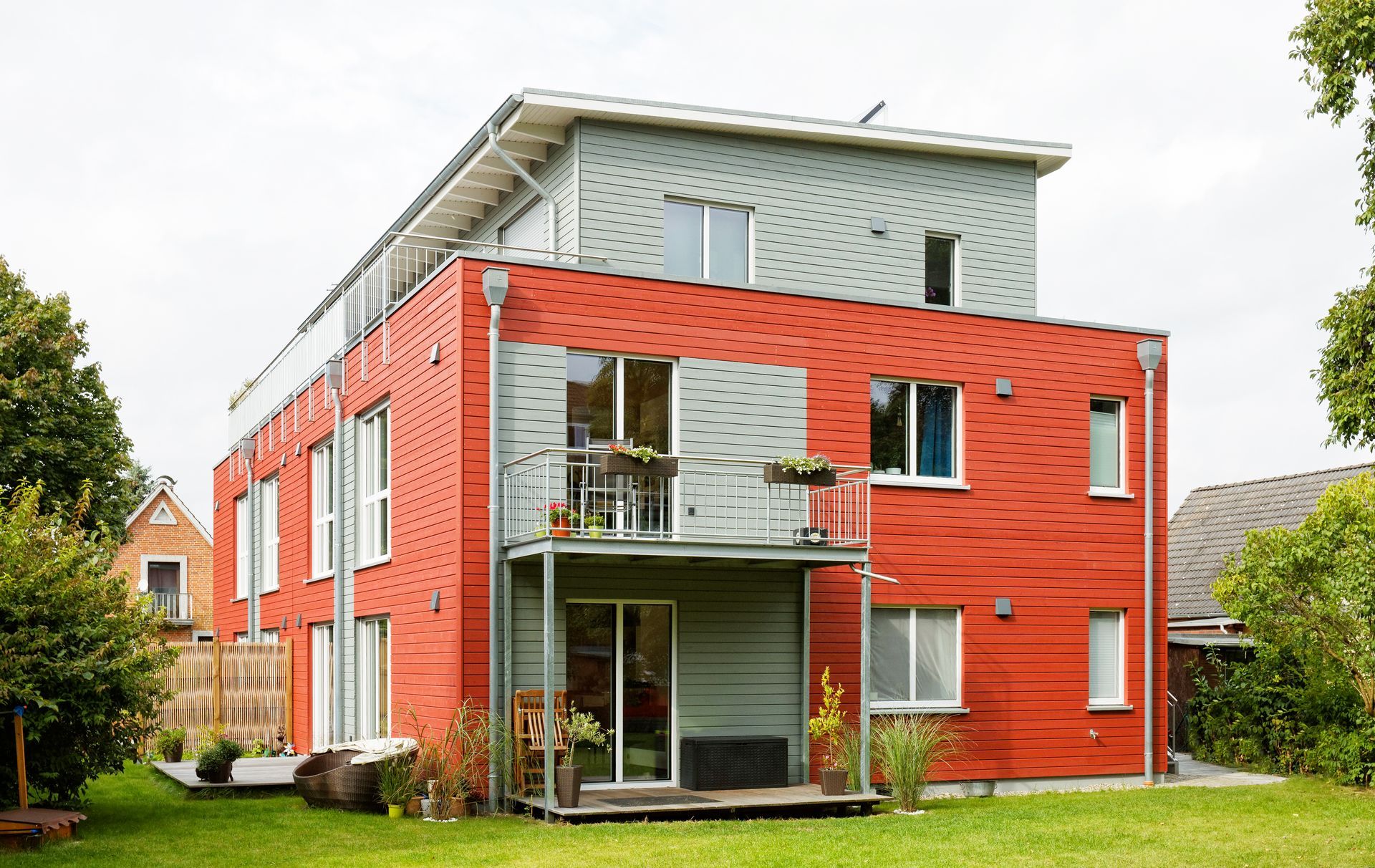 Ein Mehrfamilienhaus mit rot-grauer Holzfassade