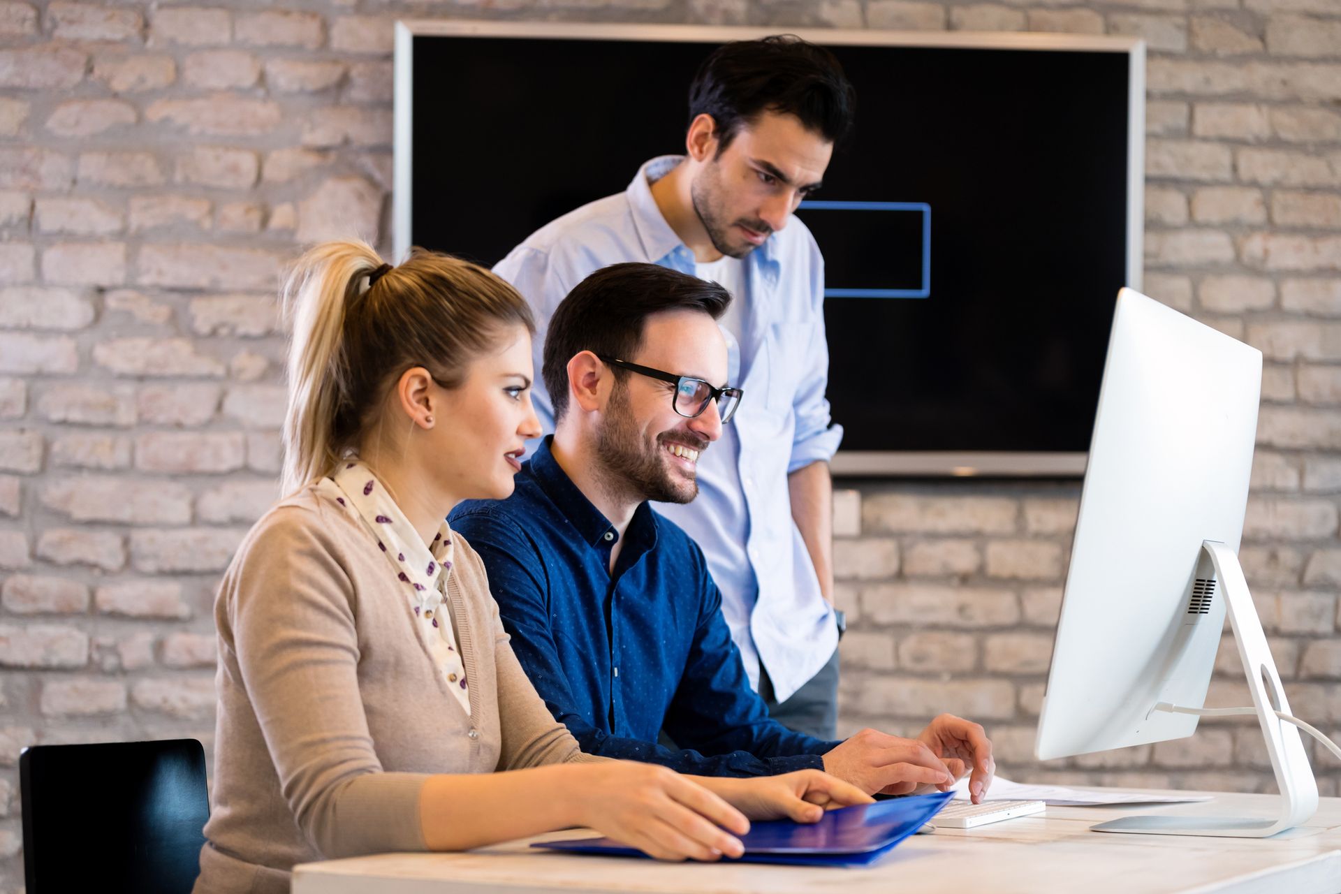 Tre colleghi riuniti attorno allo schermo di un computer. 