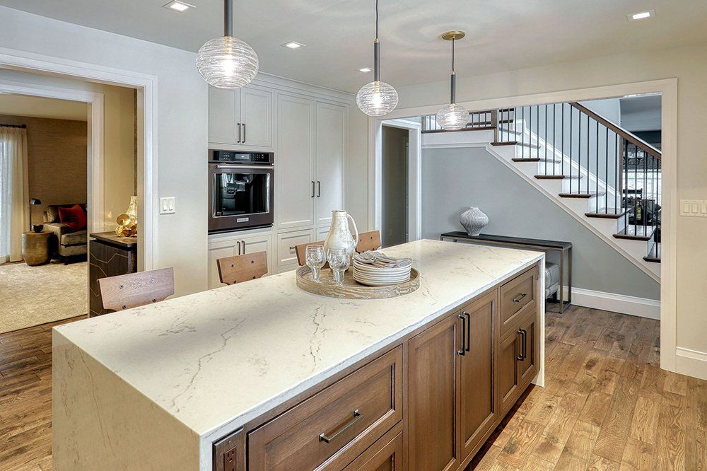 A kitchen with a large island and a staircase in the background