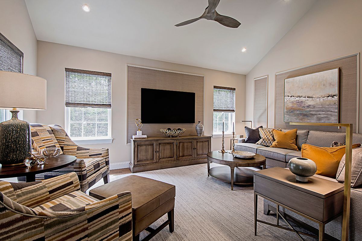 A living room with a ceiling fan and a flat screen tv