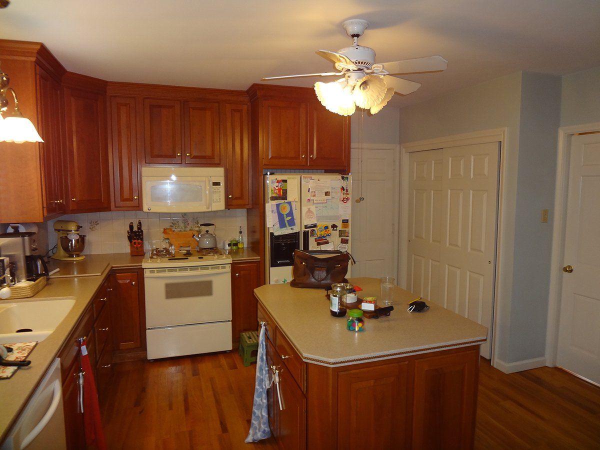 A kitchen with wooden cabinets and a ceiling fan