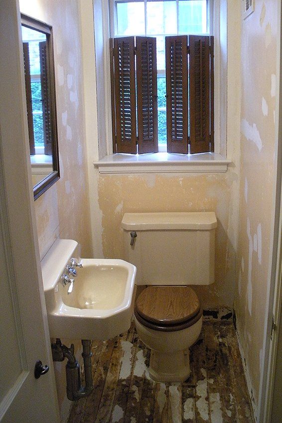 A bathroom with a toilet sink and shutters on the window