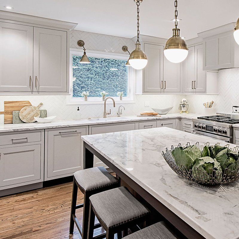 A kitchen with white cabinets and a marble counter top