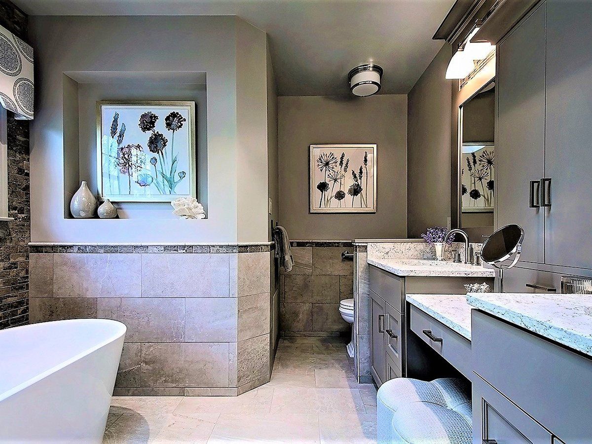A bathroom with a tub , sink , mirror and picture on the wall