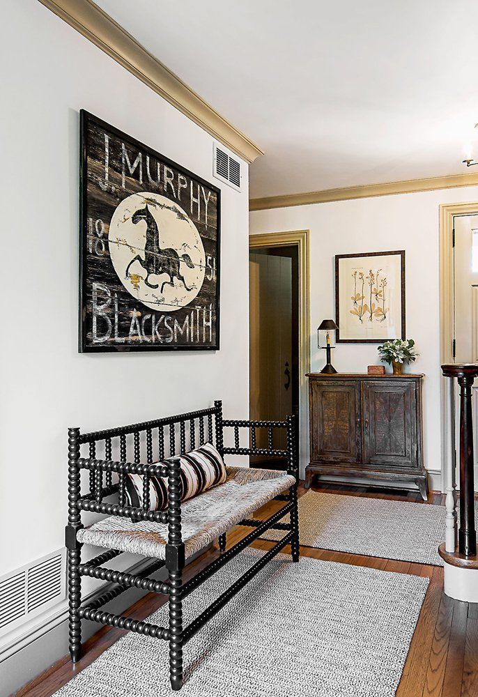 A hallway with a bench and a painting on the wall that says j. murphy blacksmith