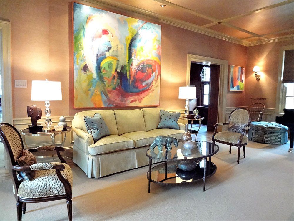 A living room with a large painting on the wall above the couch