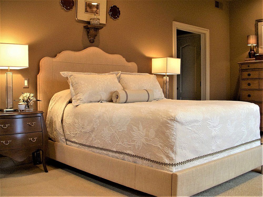 A bedroom with a bed dresser and two lamps