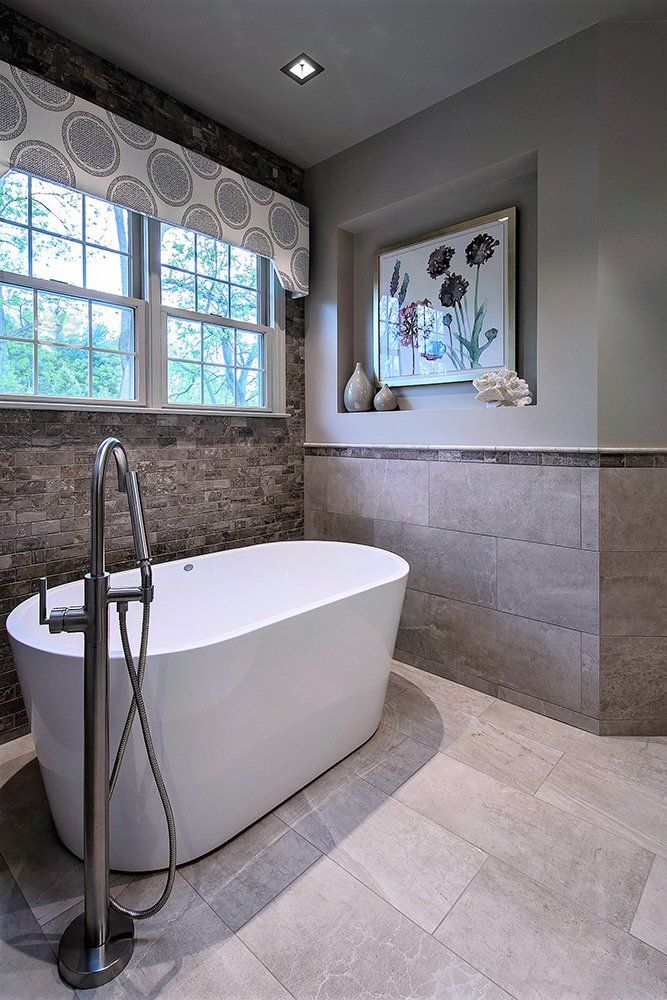 A bathtub in a bathroom with a picture on the wall above it