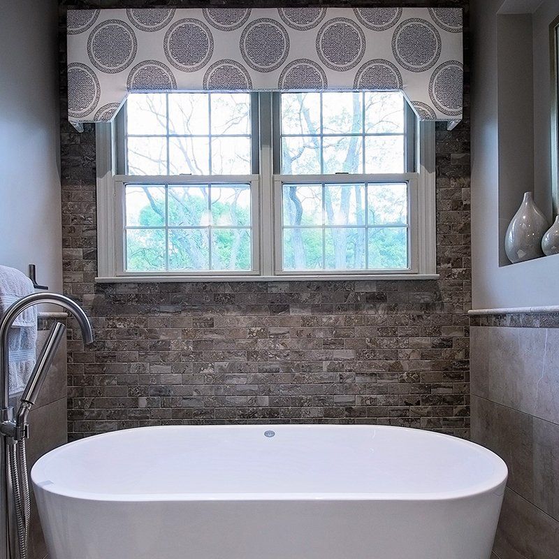 A bathtub in a bathroom next to a window