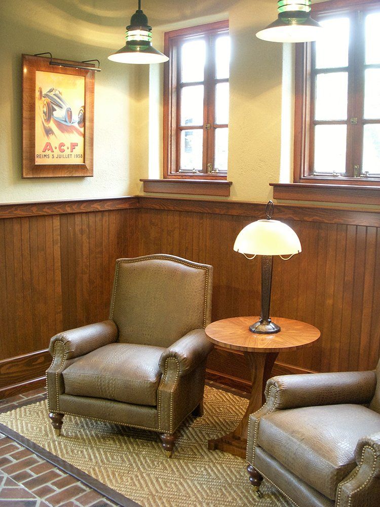 Two chairs and a table in a room with a picture on the wall that says a.e.t.