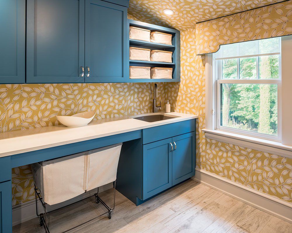 A laundry room with blue cabinets and yellow wallpaper
