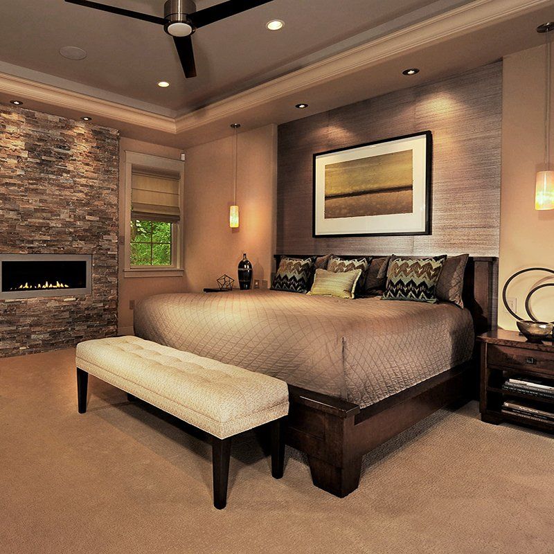 A bedroom with a large bed a bench and a fireplace