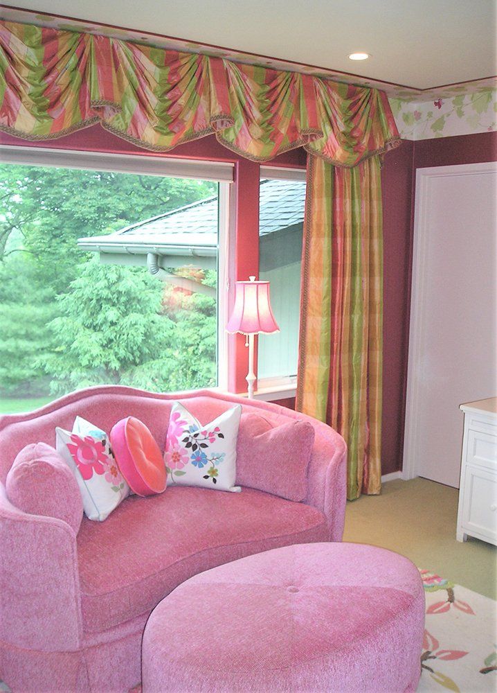 A living room with a pink couch and ottoman