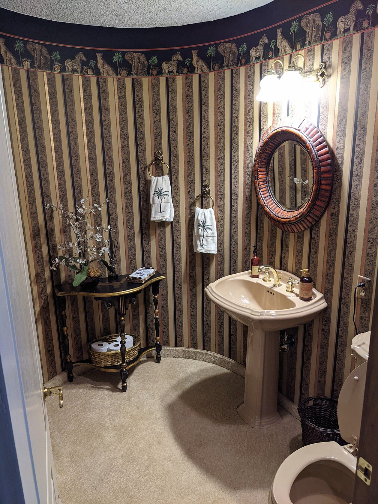 A bathroom with striped wallpaper and a pedestal sink