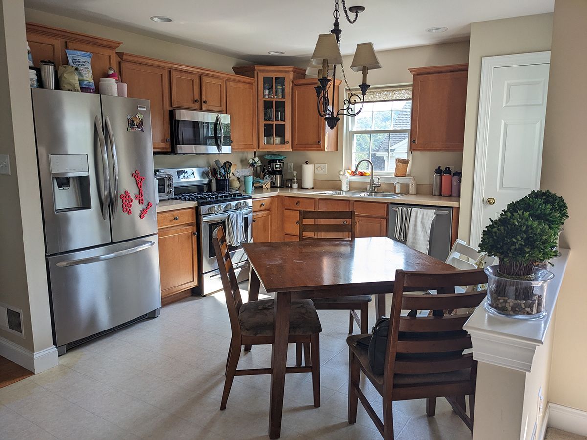 A kitchen with a table and chairs and a stainless steel refrigerator