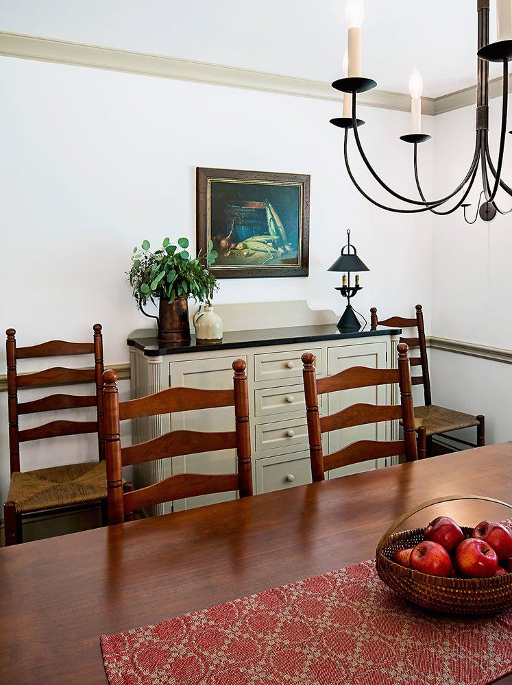 A dining room table with a basket of apples on it