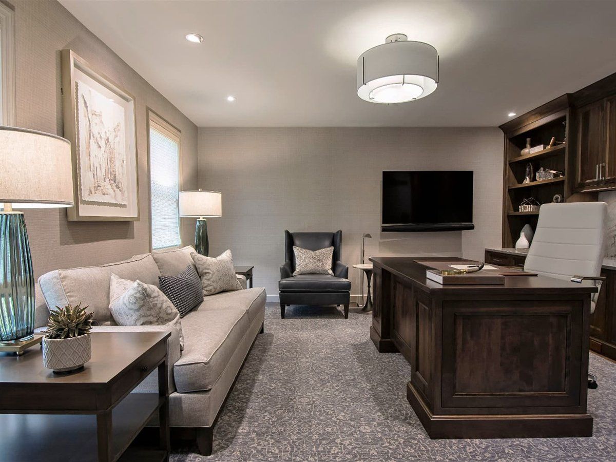 A living room with a couch , chair , desk and television