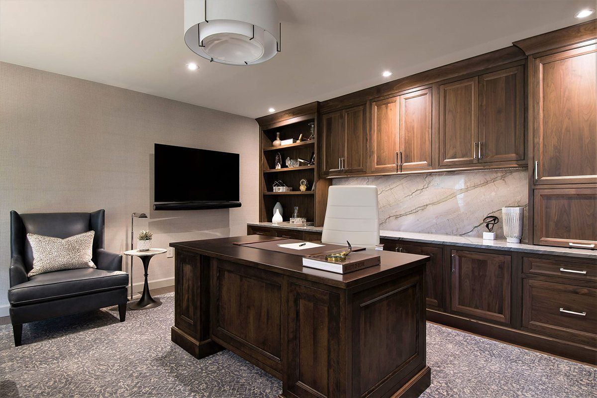 A home office with a large wooden desk and a flat screen tv