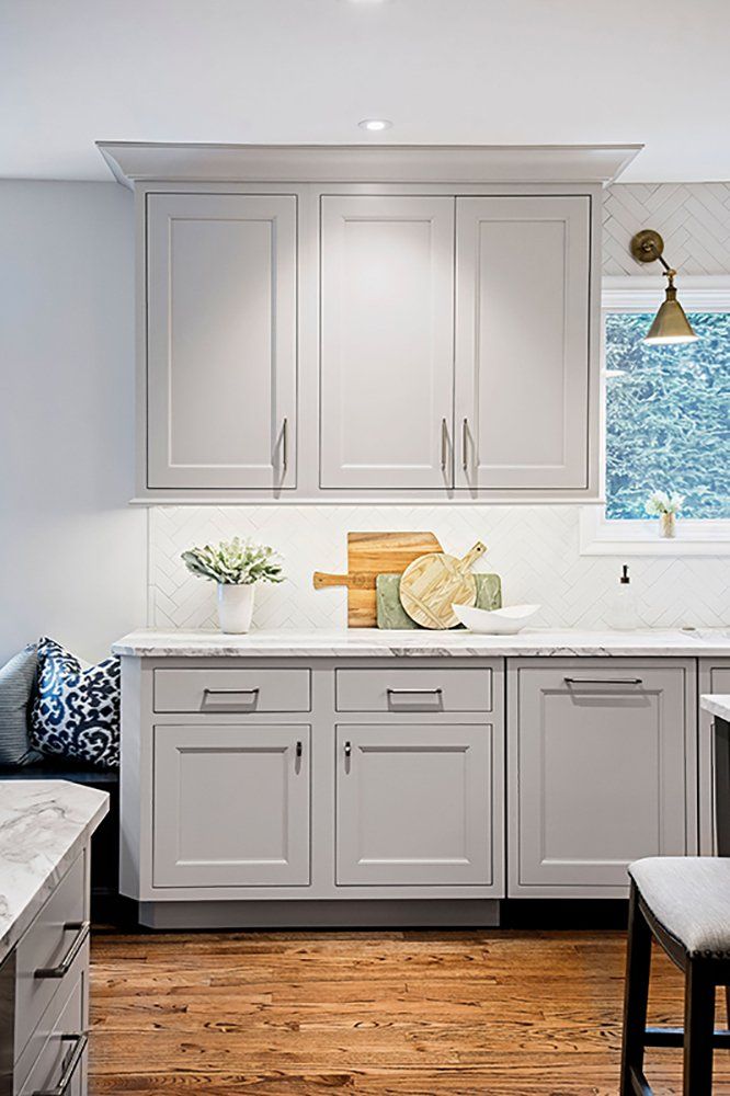 A kitchen with white cabinets and wooden floors