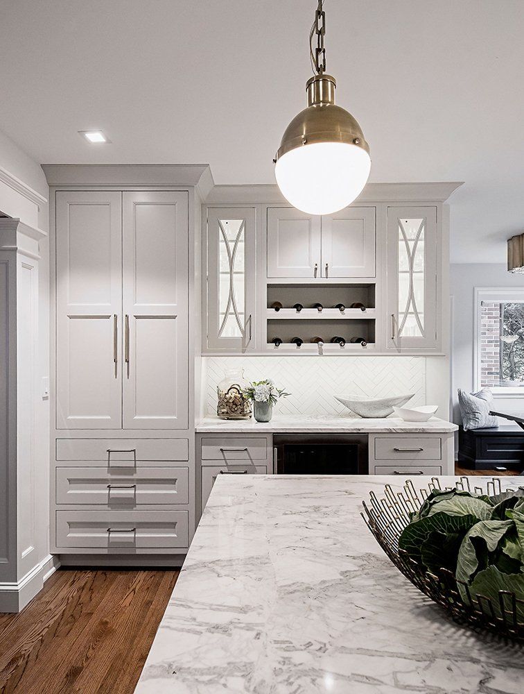 A kitchen with white cabinets and a marble counter top