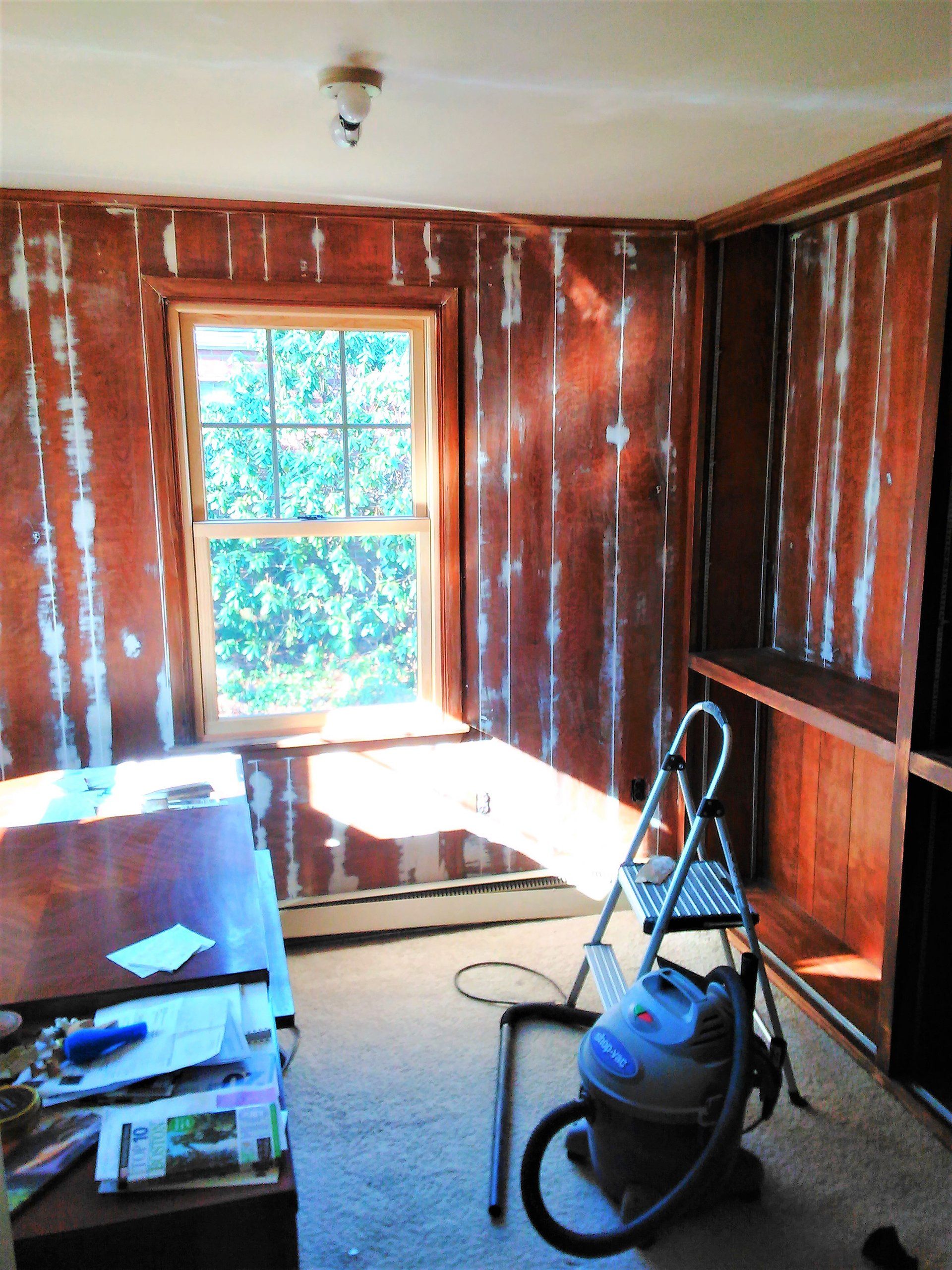 A room with a ladder and a vacuum cleaner on the floor