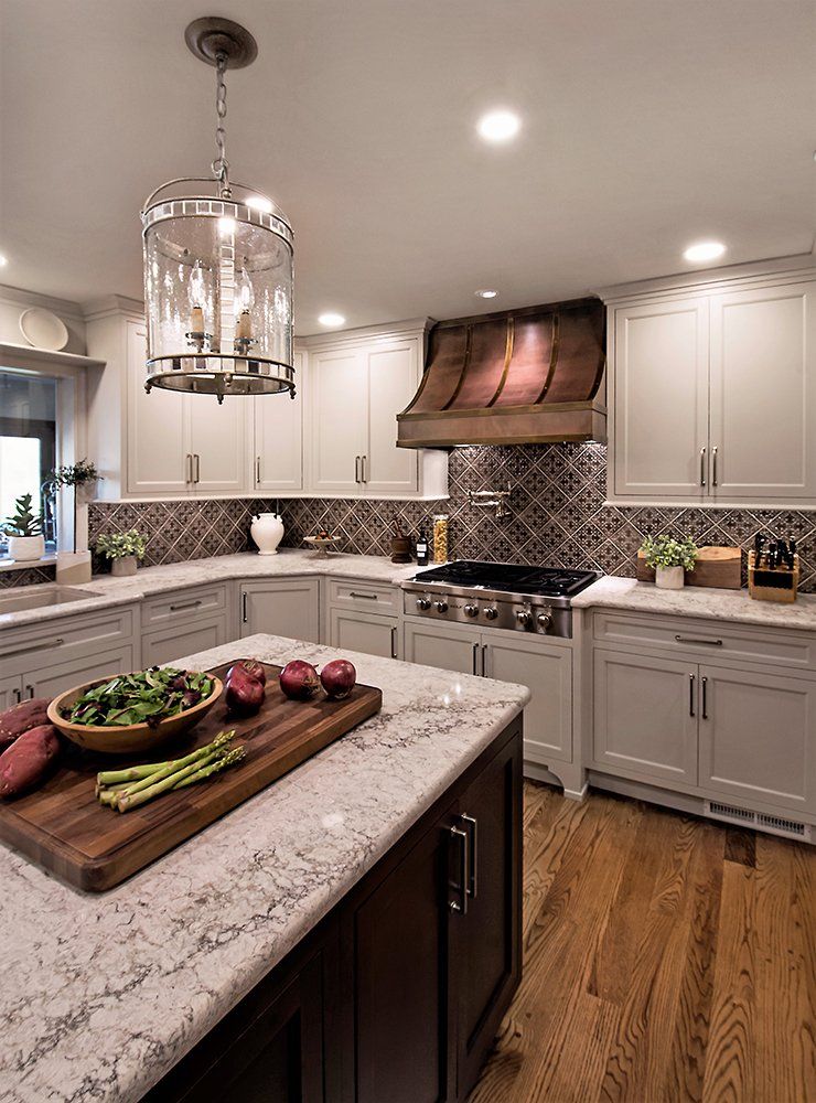 A kitchen with white cabinets and a large island with vegetables on it