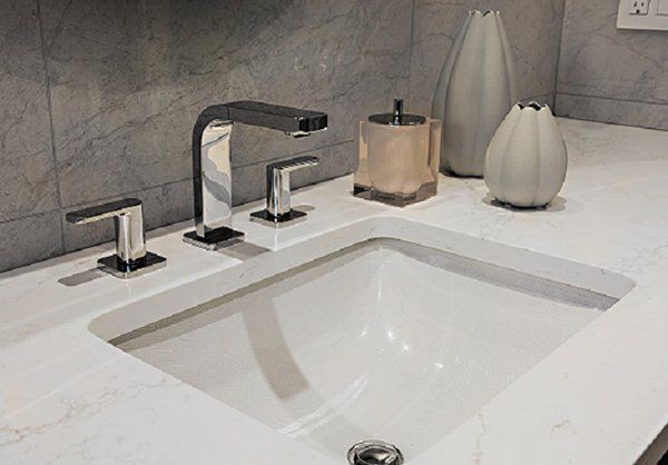 A bathroom sink with a faucet and vases on the counter.