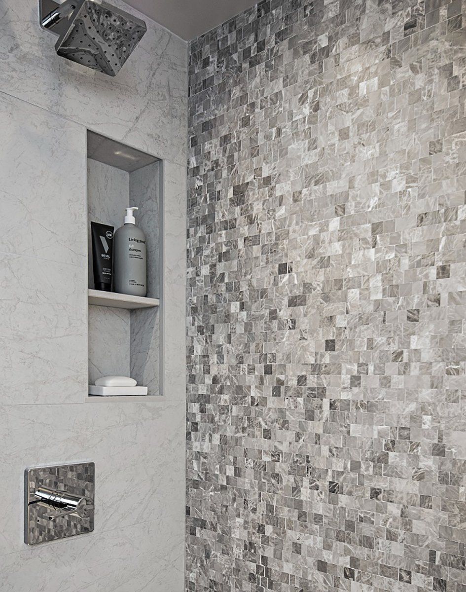 A bathroom with a shower head and a shelf with a bottle of shampoo on it.