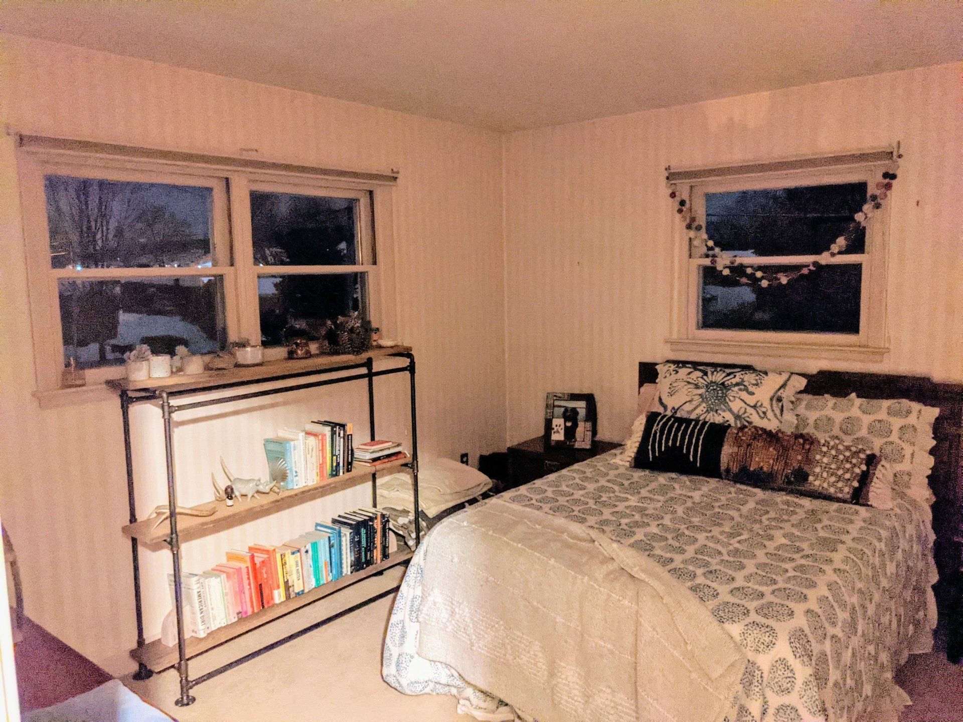 A bedroom with a bed and a bookshelf with books on it
