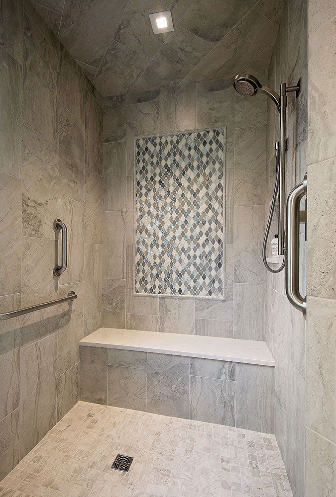 A walk in shower with a bench and a shower head.