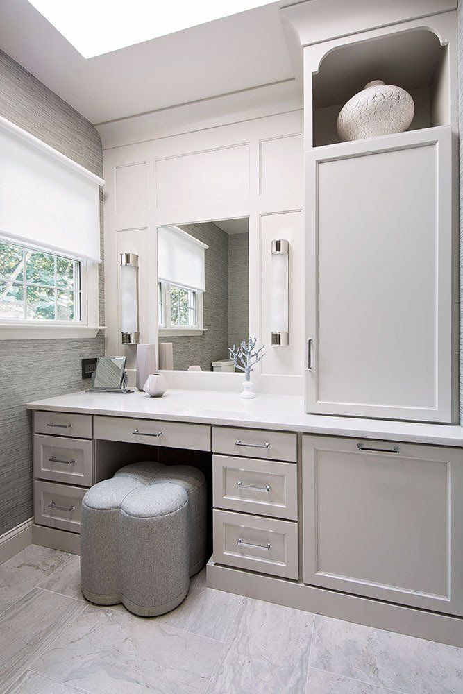 A bathroom with a vanity and two ottomans