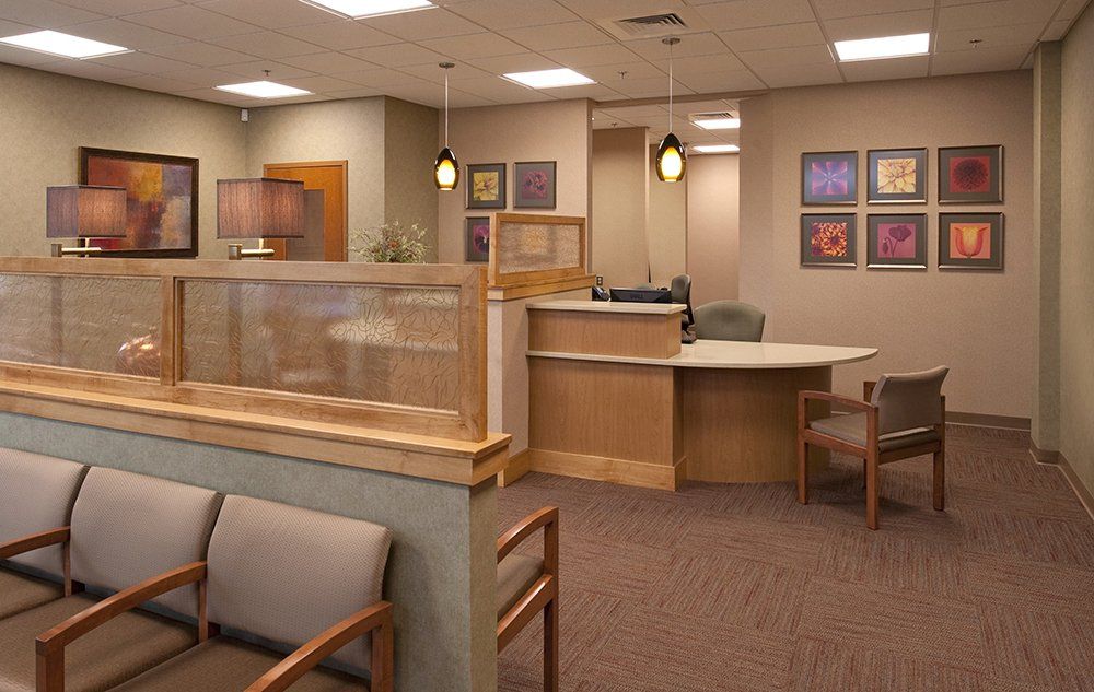 A waiting room with a desk and chairs and a wall with pictures on it