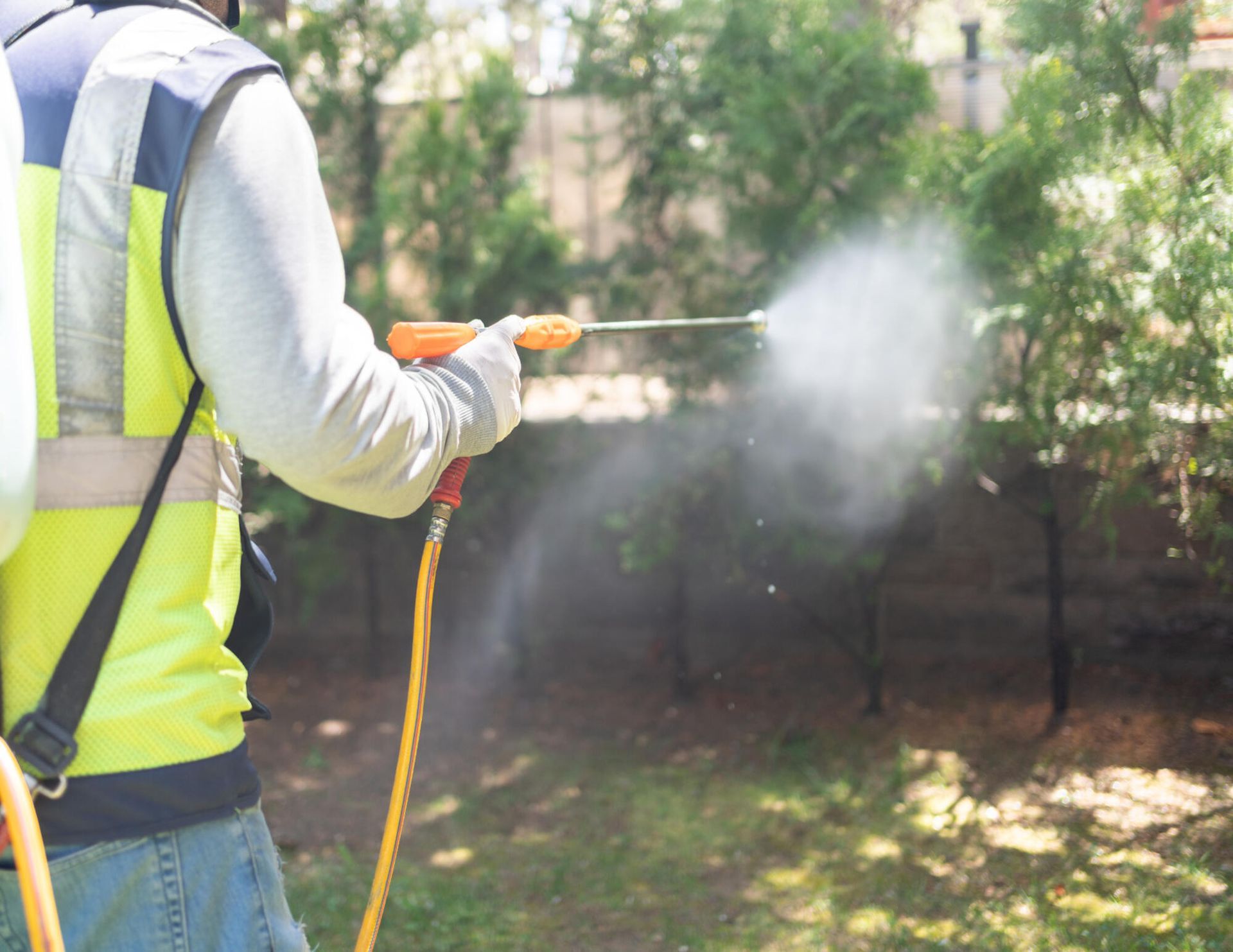 A man is spraying a lawn with a sprayer.