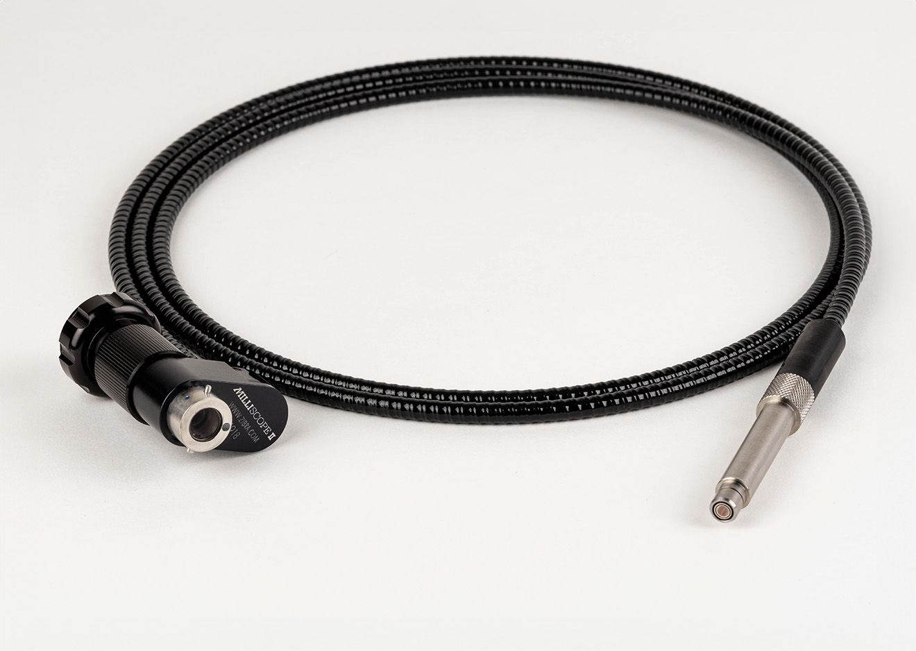 A black cable with a metal tip is sitting on a white surface