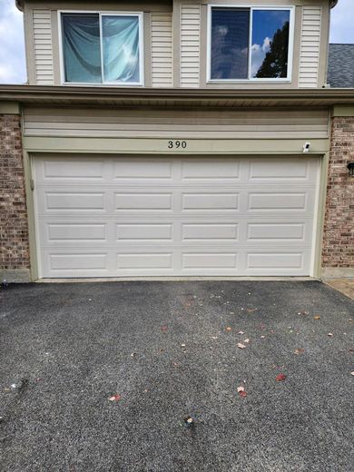 A white garage door is sitting in front of a brick house.