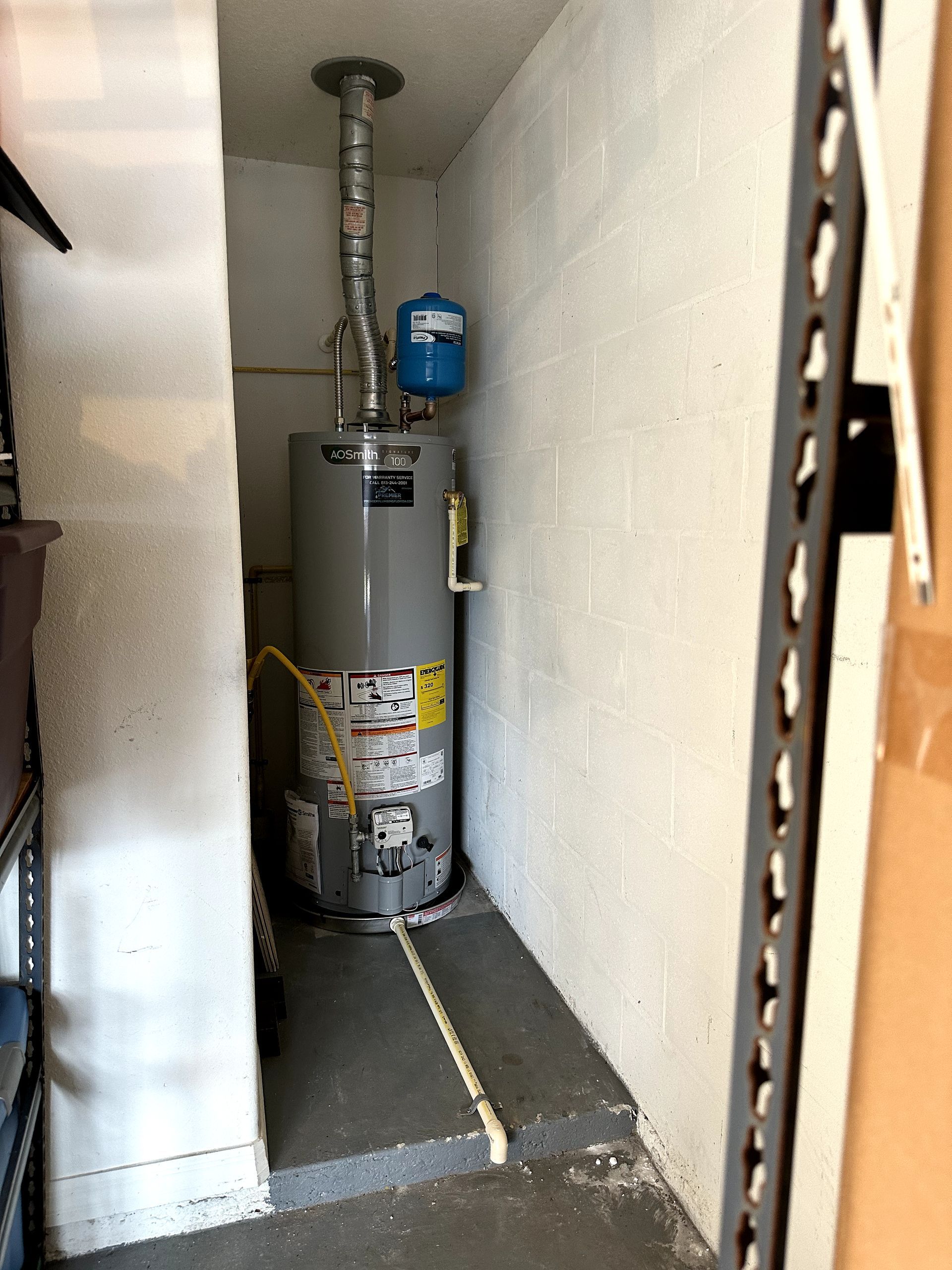 A water heater is sitting in a corner of a room.