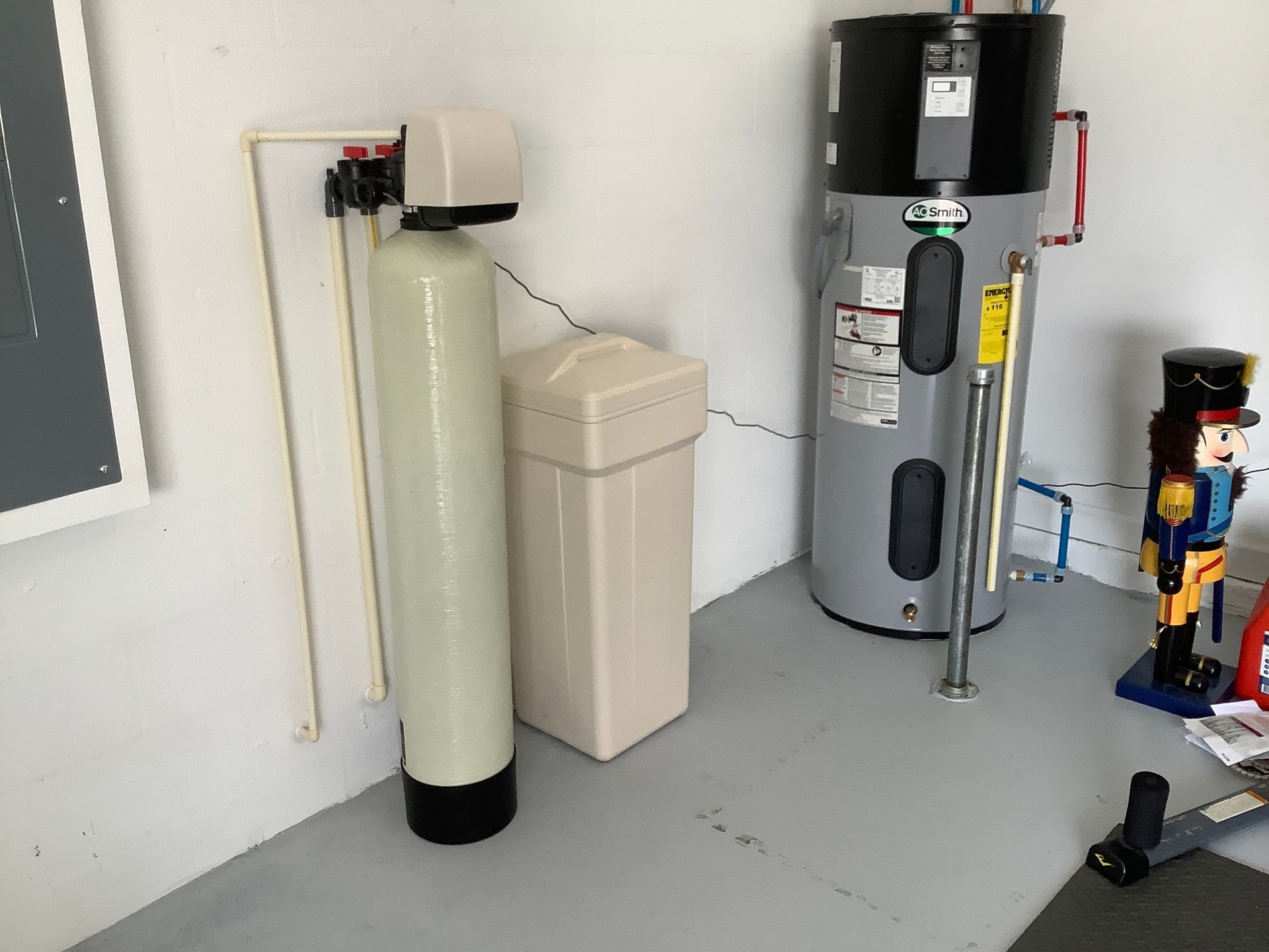 A water filter is sitting next to a water heater in a room.